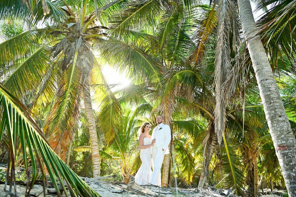 Bride and groom standing below palm tree