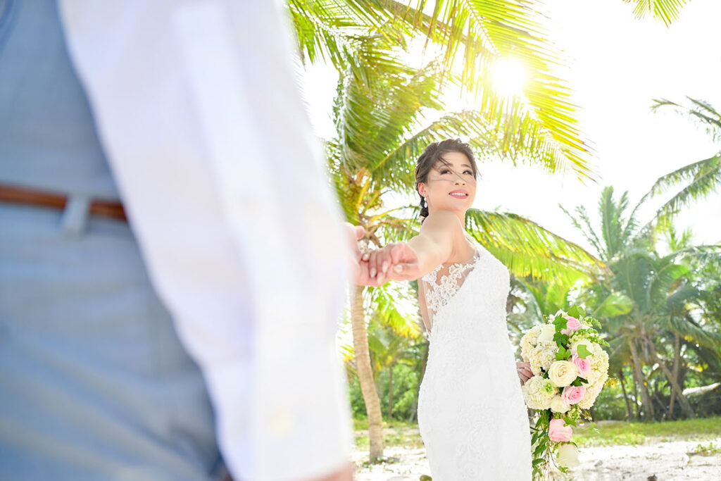 Bride is holding and leading groom on a beach