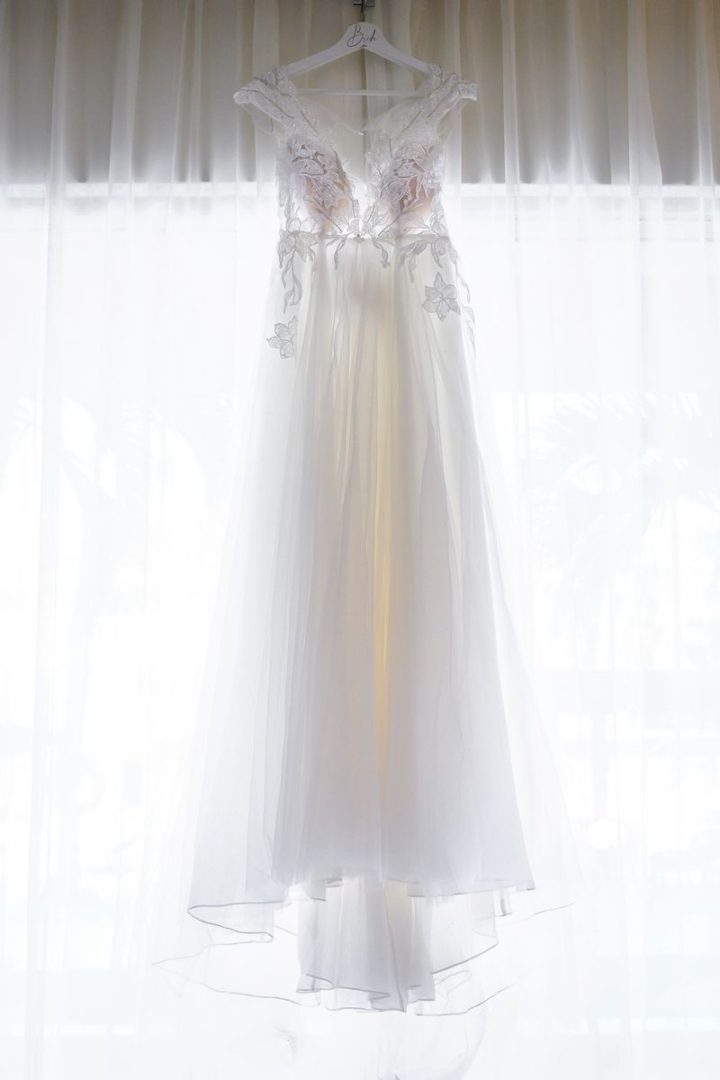white wedding dress in front of curtain