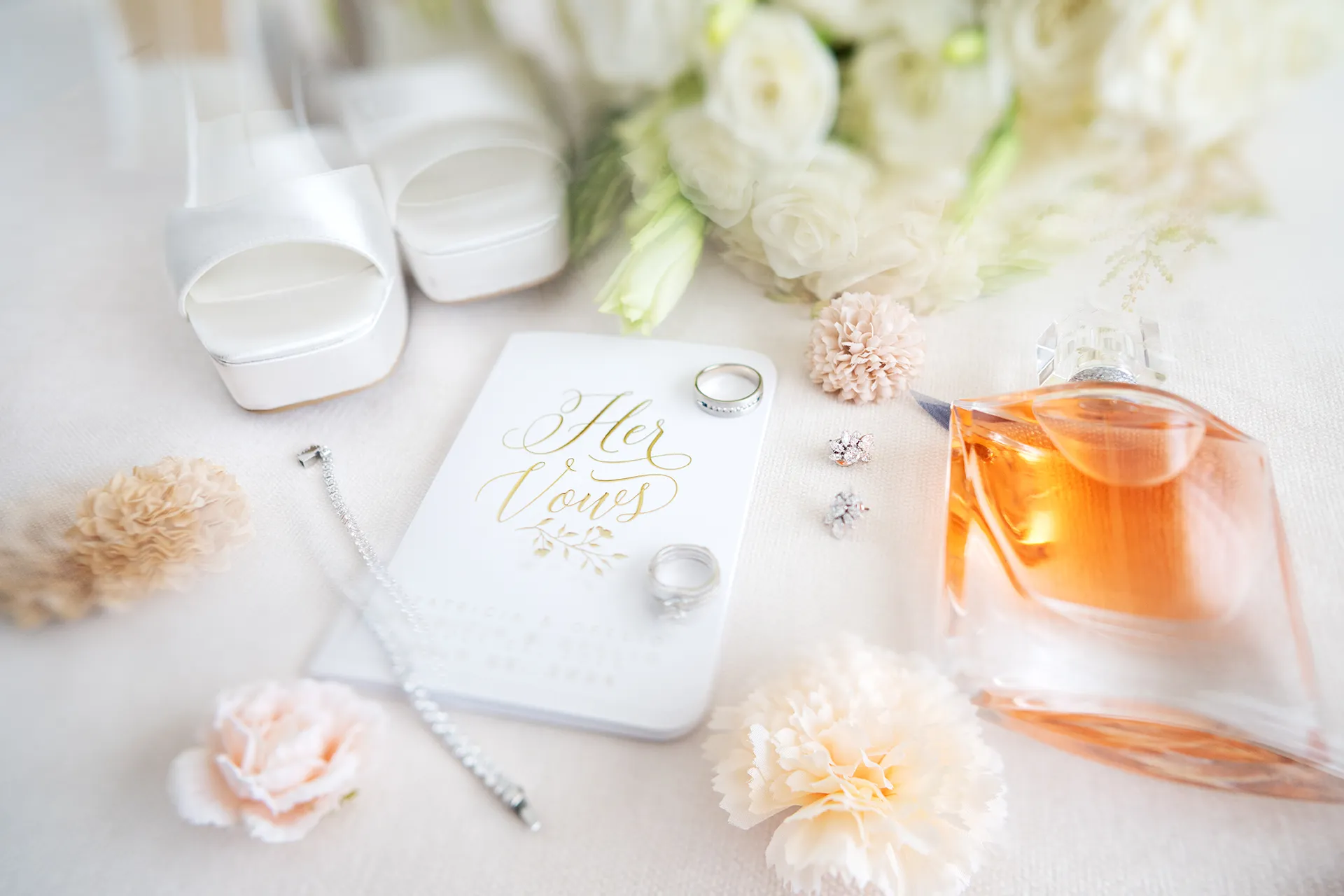 Bridal details including vows booklet, perfume, rings, and shoes for Pearl Beach Club wedding