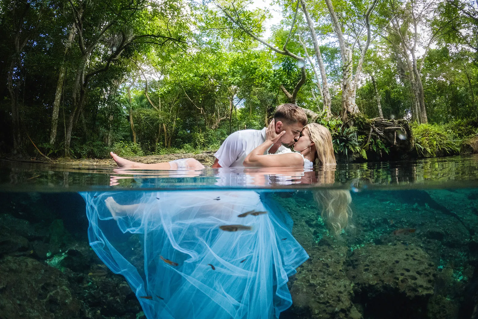 Couple kissing at the surface of a cenote with the wedding dress flowing underwater near Punta Cana