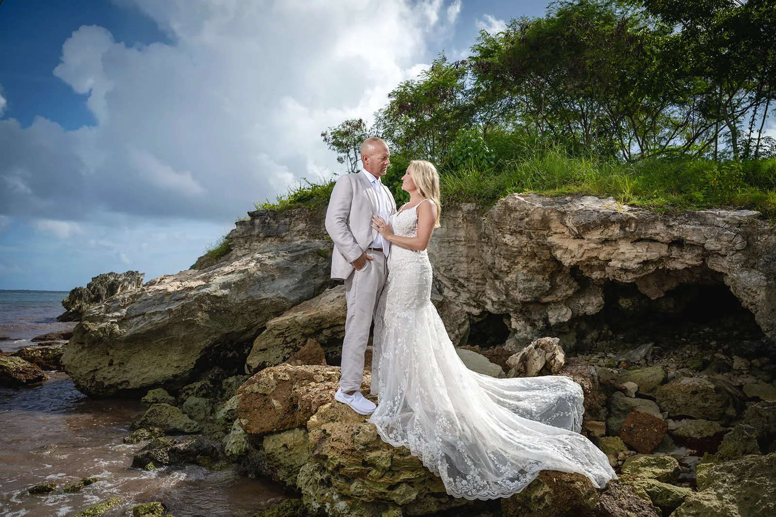 Bride in a lace gown and groom posing on coastal rocks near Macao Beach in Punta Cana