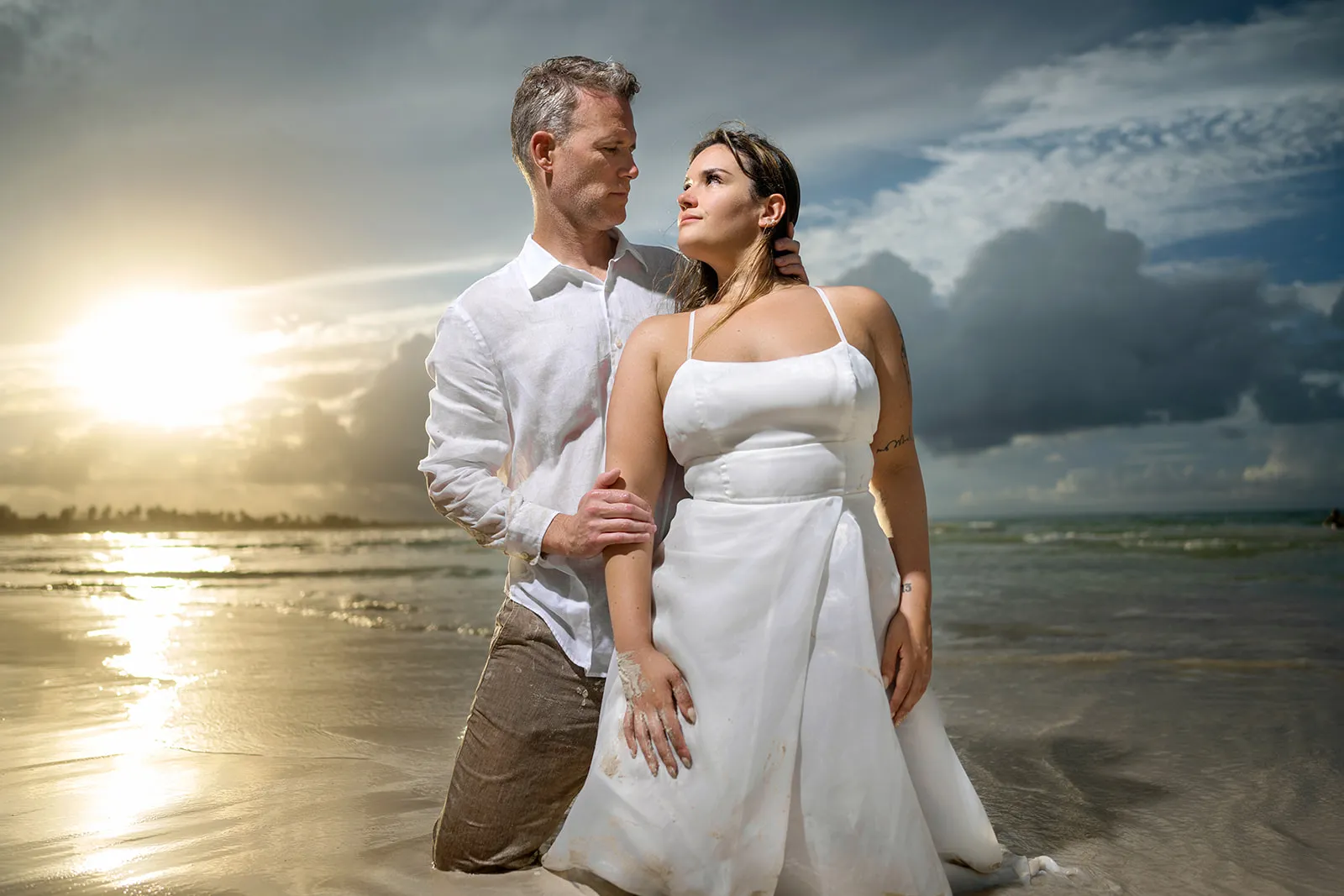 Bride in a simple white dress with sand on the fabric at sunset during a Punta Cana Trash the Dress shoot