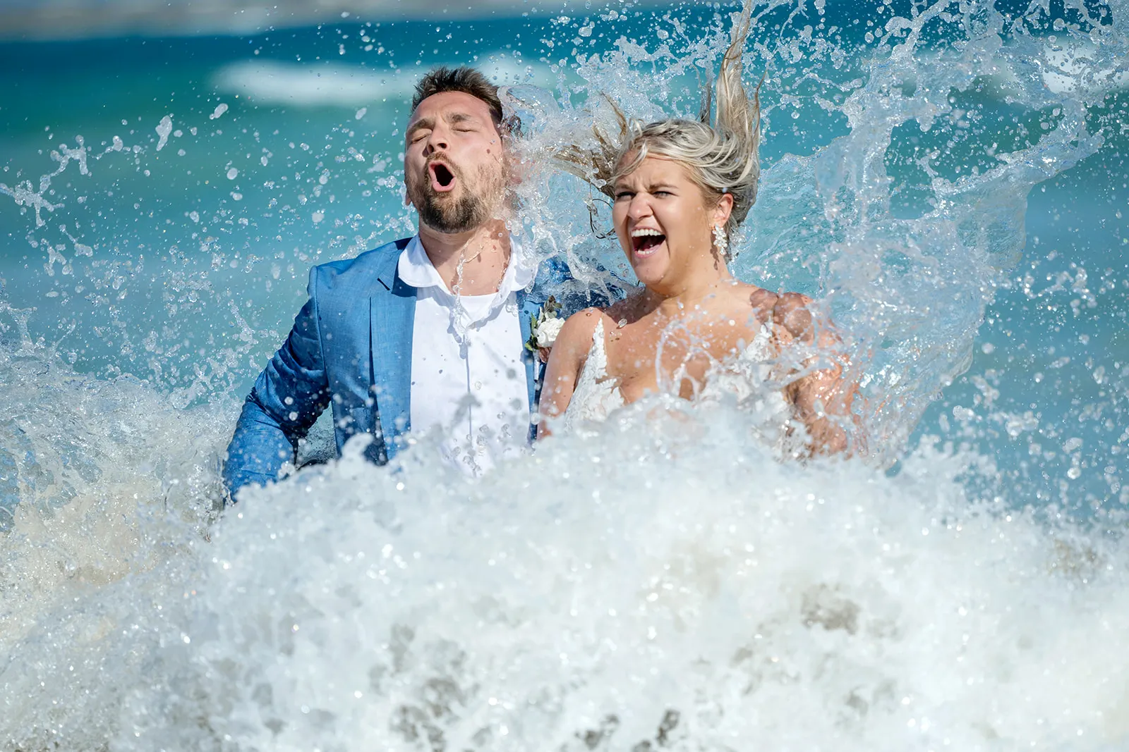 Bride and groom laughing as an ocean wave crashes over them during a Punta Cana beach session Bride and groom laughing as an ocean wave crashes over them during a Punta Cana beach session