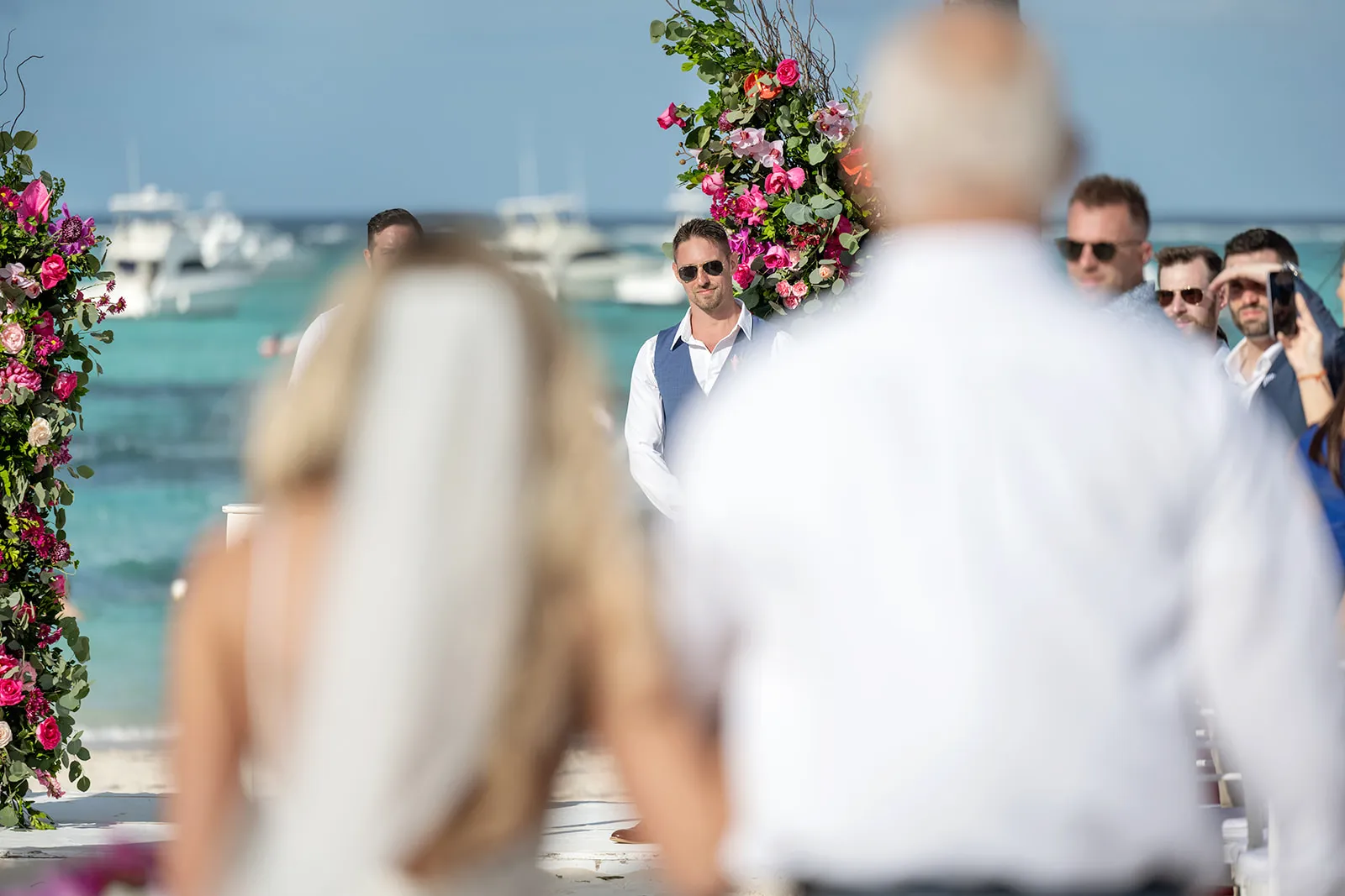 Groom in a blue vest watching his bride walk down the aisle at Jellyfish Restaurant Punta Cana