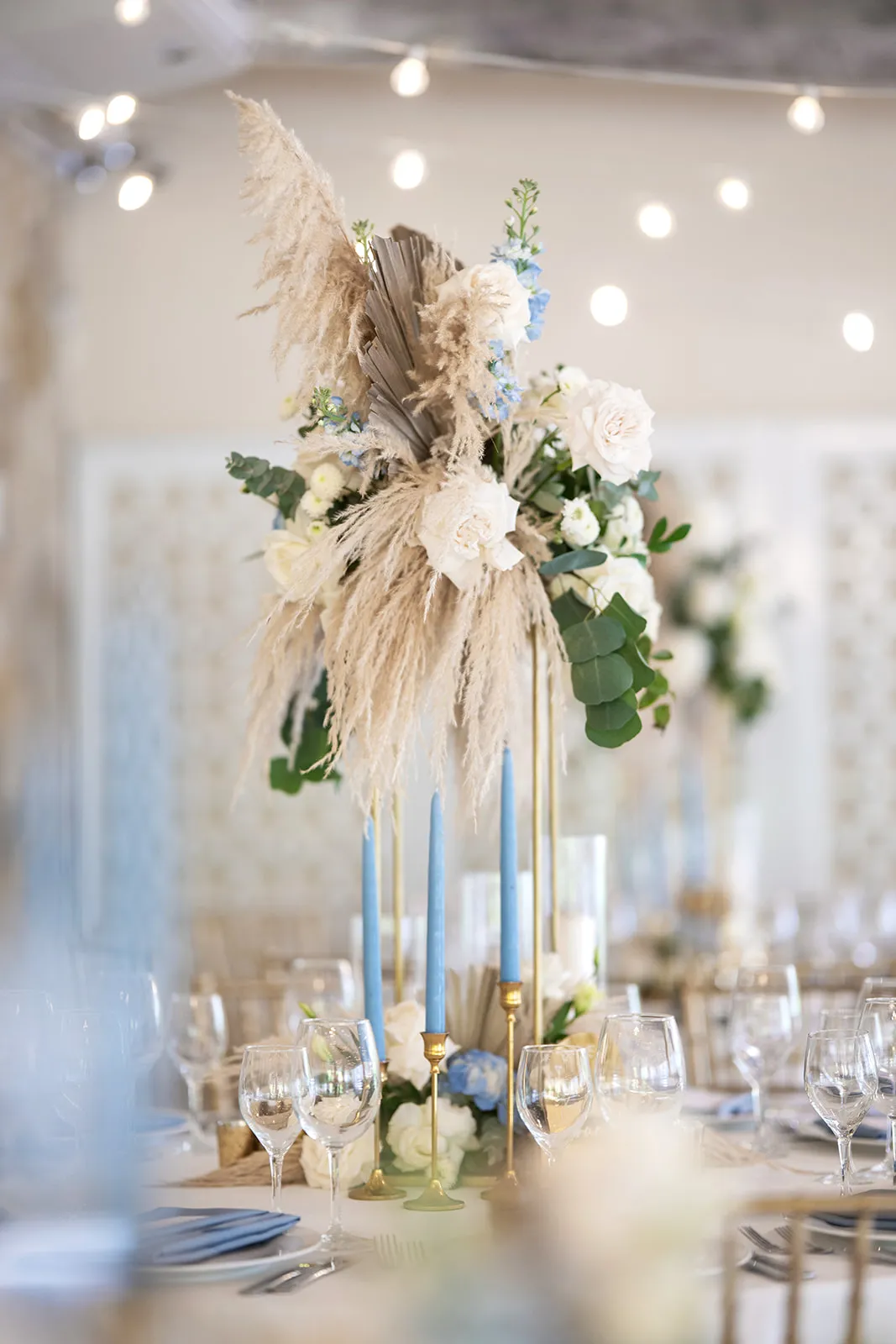 Tall white floral and pampas centerpiece with blue candles at the Kukua Beach Club wedding reception
