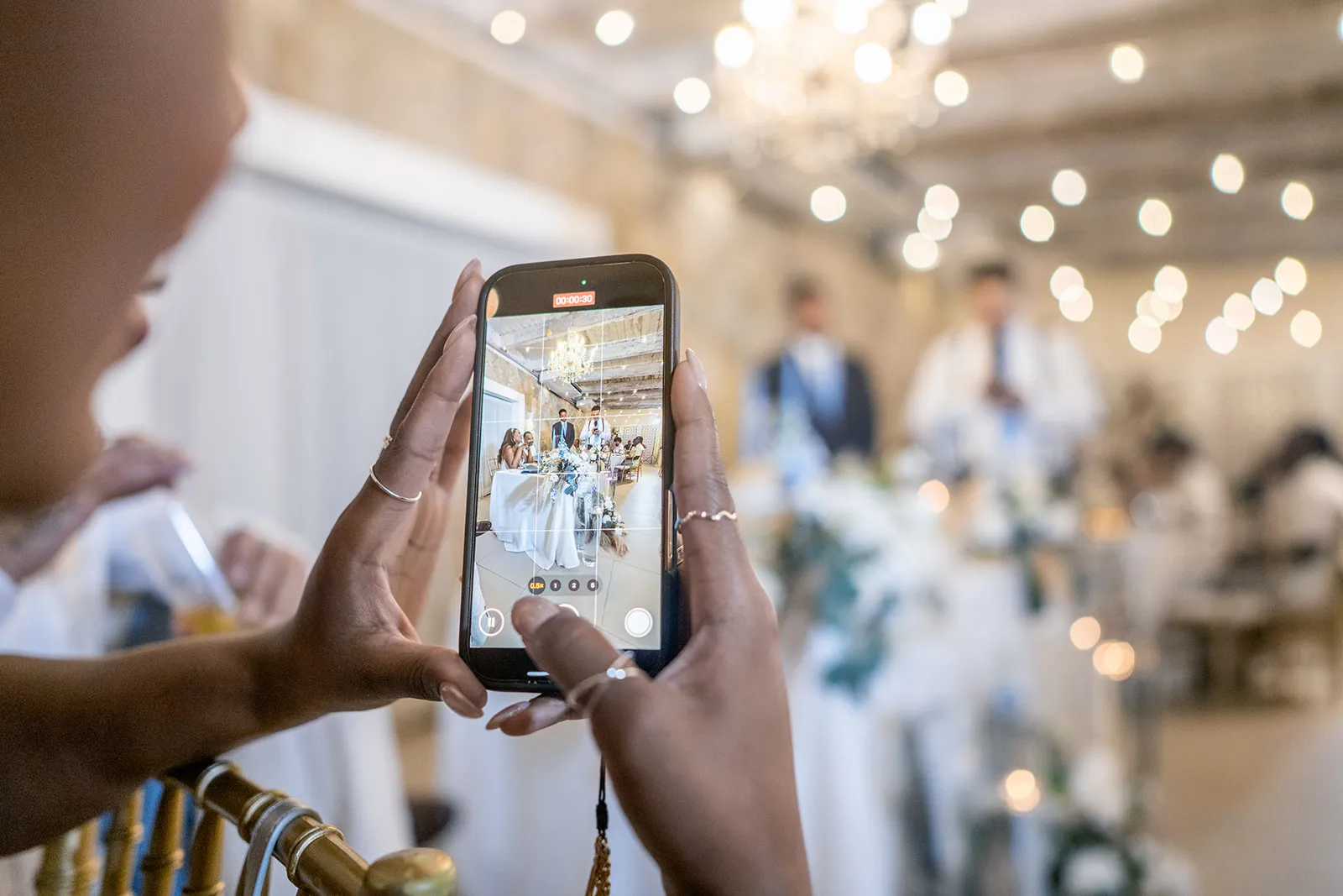Guest recording the head table on her phone during the Kukua Beach Club wedding reception Guest recording the head table on her phone during the Kukua Beach Club wedding reception