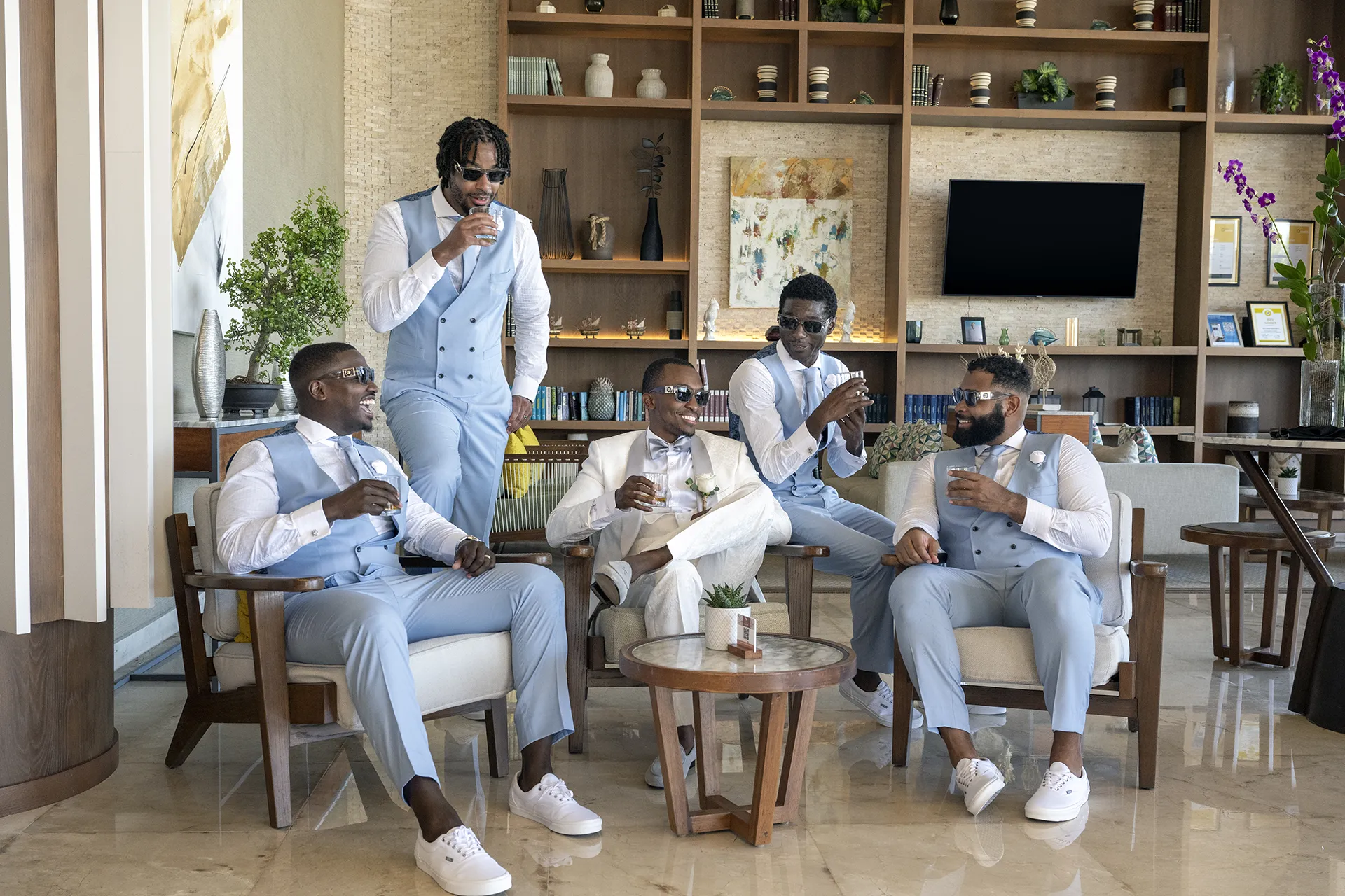 light-blue-groomsmen-beach-wedding-attire Groomsmen in light blue vests, matching trousers and white sneakers relaxing with the groom in a white suit