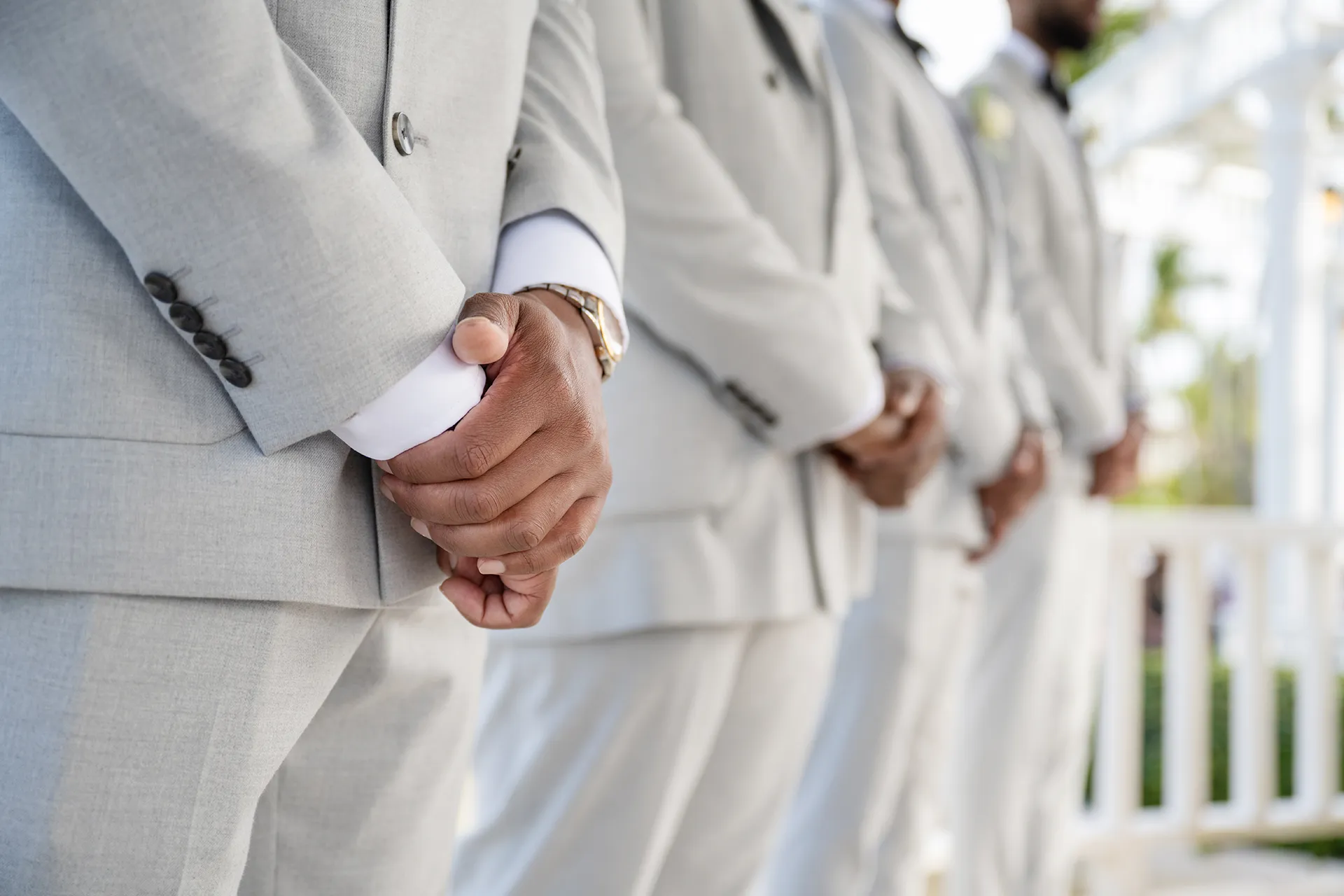 Groomsmen in matching light gray suits standing in a row at a Punta Cana beach ceremony