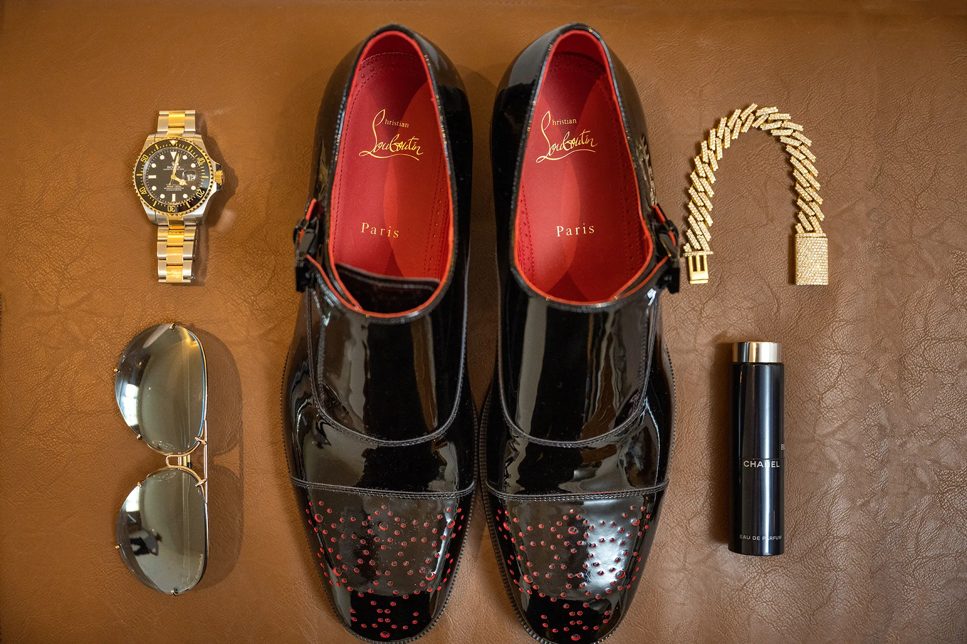 luxury-groom-accessories-wedding-shoes-watch Groom's black patent leather dress shoes laid out with a watch, sunglasses and bracelet for getting-ready photos