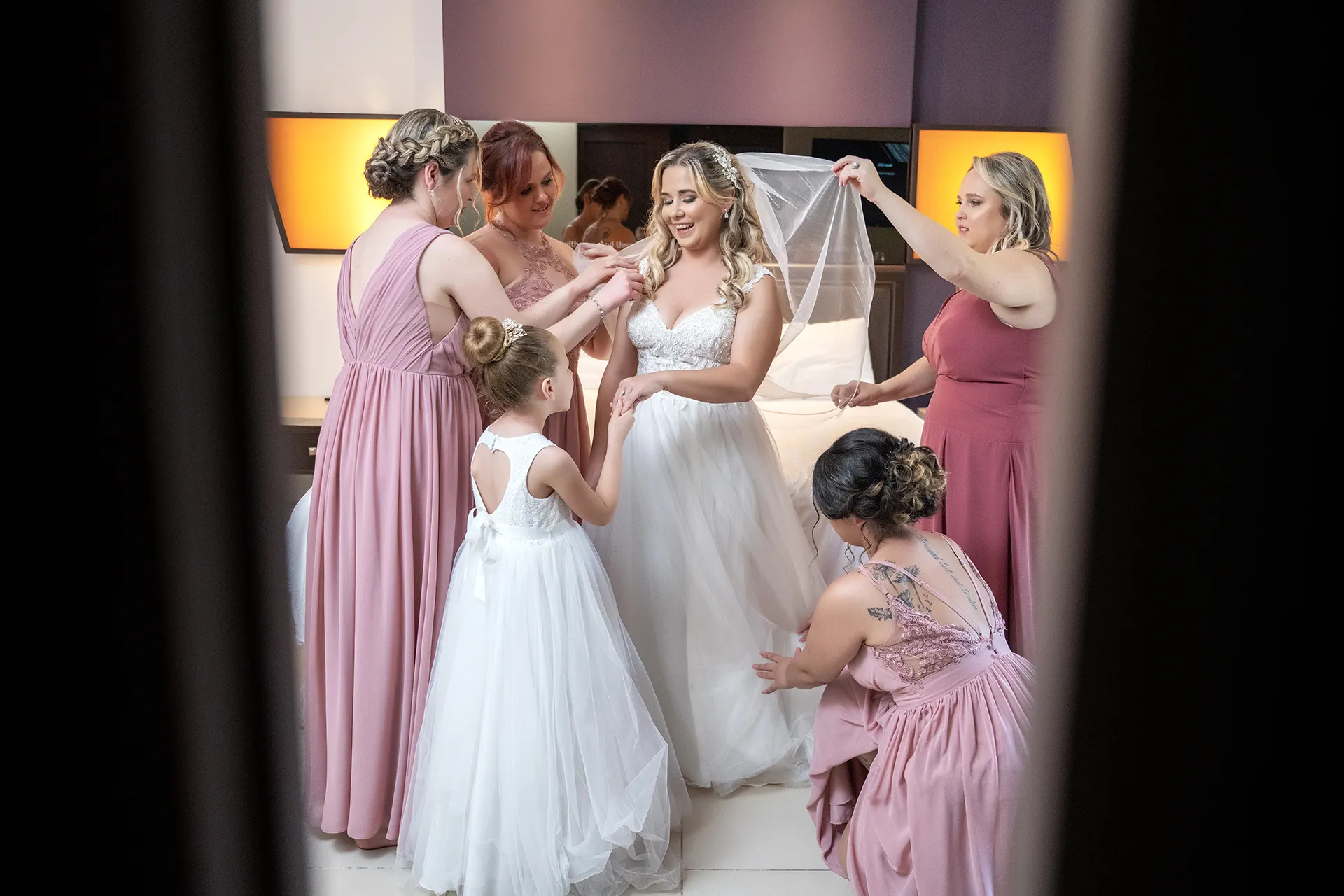 punta-cana-bride-bridesmaids-getting-ready-outfits Bride getting ready with bridesmaids in dusty pink dresses and a flower girl holding her veil
