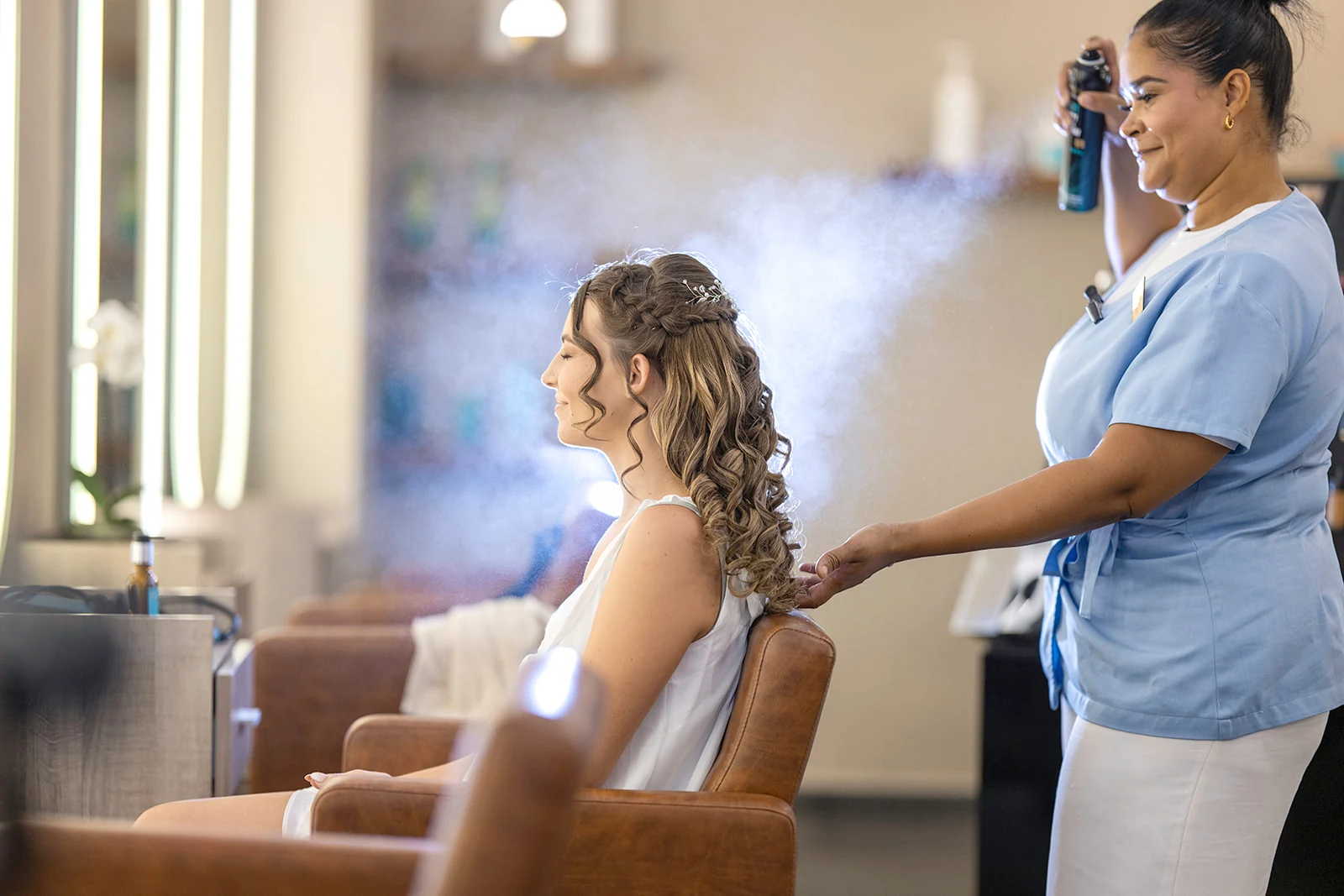 dreams-flora-bride-hair-styling Bride having her braided curls finished with hairspray by a stylist in the Dreams Flora spa salon