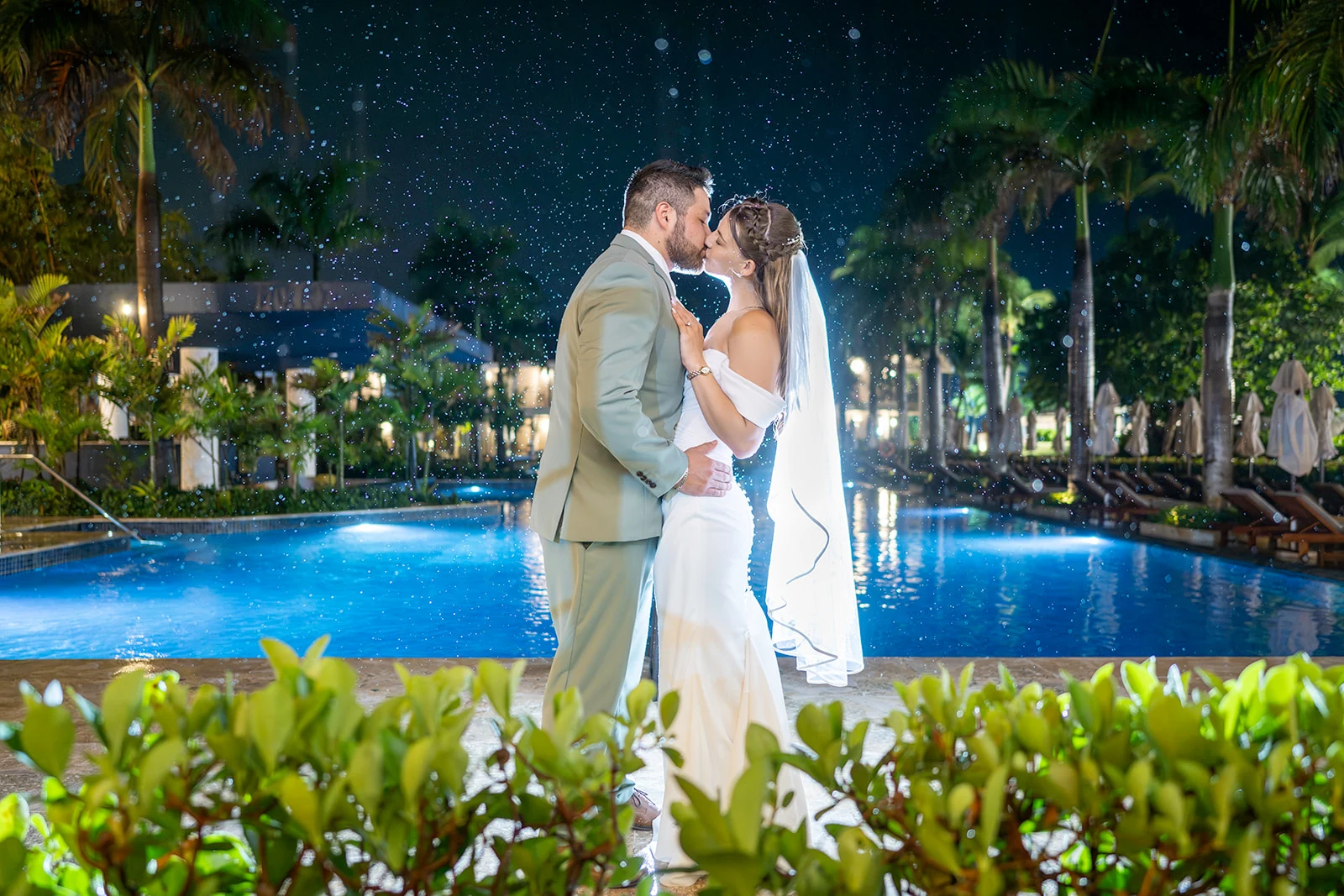 dreams-flora-night-wedding-portrait-pool Bride and groom kissing beside an illuminated pool surrounded by palms at Dreams Flora at night