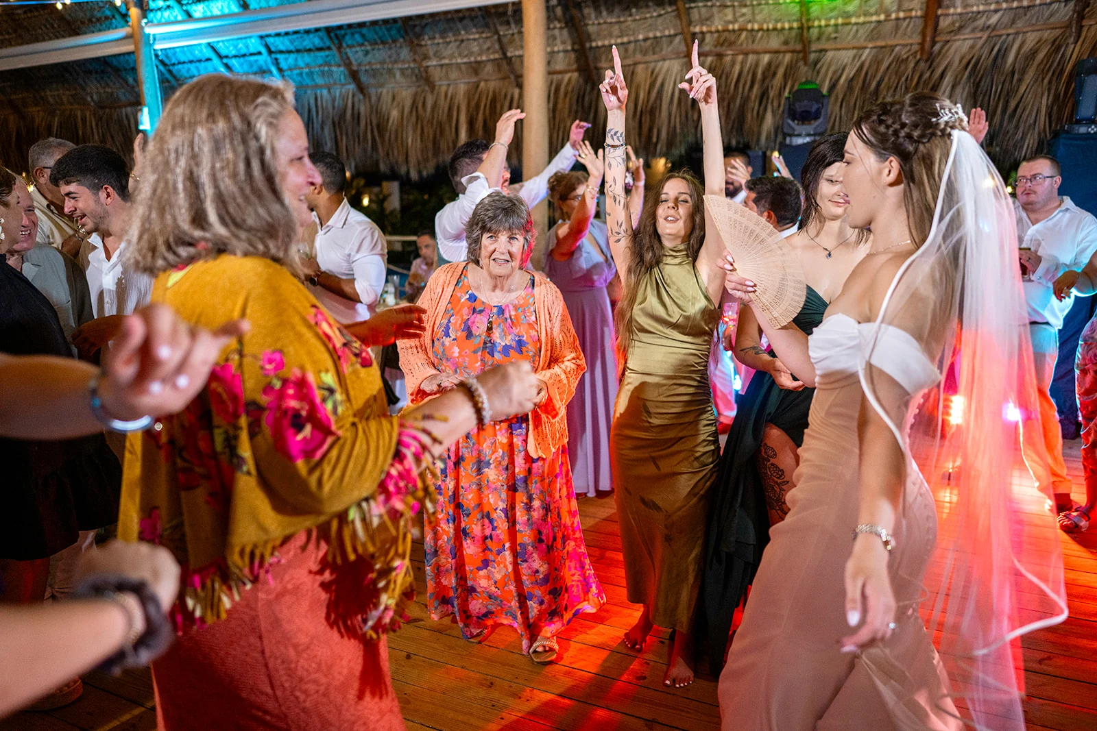 dreams-flora-wedding-reception-dancing Bride dancing with her guests on a wooden dance floor under colorful lights at the reception